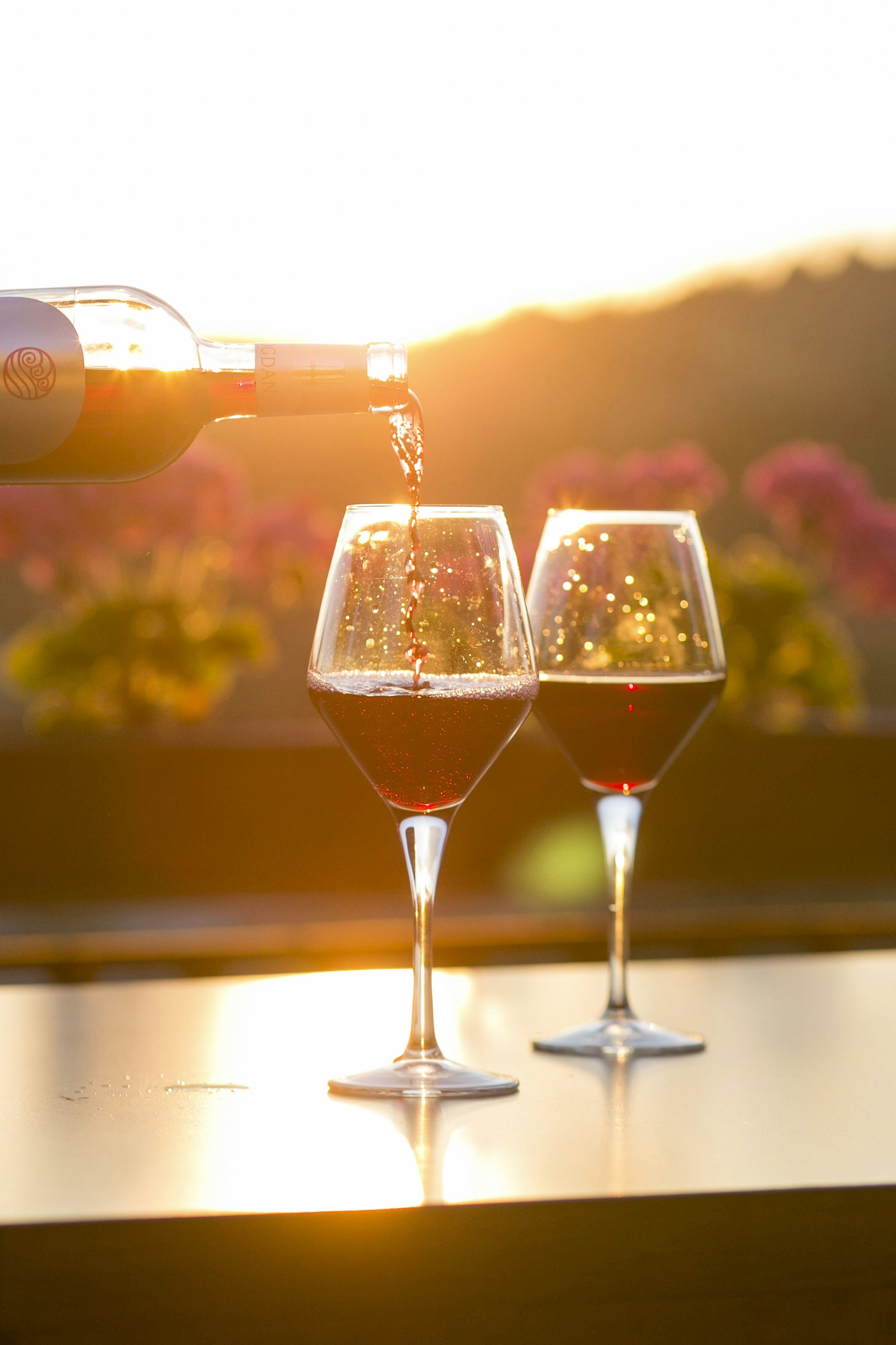 Two glasses of red wine being poured in warm afternoon light